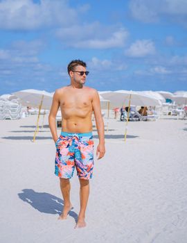 Miami beach, young men on the beach, lifeguard hut Miami beach Florida. caucasian men on the beach during sunset. European men shirtless with swim short