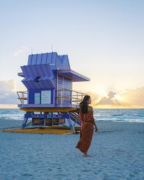 Miami Beach, a couple on the beach at Miami Florida, lifeguard hut Miami Asian women and caucasian men on the beach during sunset. Woman watching sunset on the beach