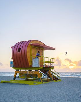 Miami Beach, a couple on the beach at Miami Florida, lifeguard hut Miami Asian women and caucasian men on the beach during sunset. Woman watching sunset on the beach