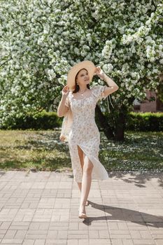 An attractive long-haired woman walks in the spring in the park of blooming apple trees. Spring portrait of a woman