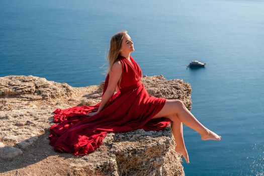 A woman in a red flying dress fluttering in the wind, against the backdrop of the sea