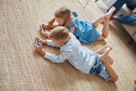 little brother and sister playing entertaining games on their smartphones. close-up.