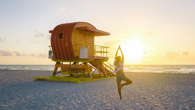 Miami Beach, a couple on the beach at Miami Florida, lifeguard hut Miami Asian women and caucasian men on the beach during sunset. Woman watching sunset on the beach