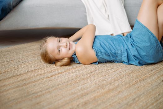little girl is playing lying on the floor in the living room . photo with a copy space.