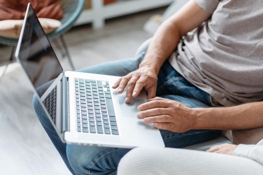 image of a man using a laptop in his apartment. close-up.