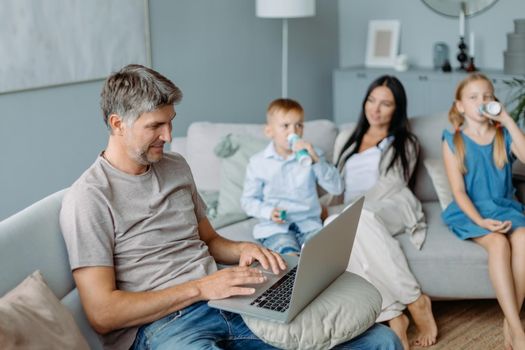 smiling father using a laptop in a cozy living room. concept of family pastime.