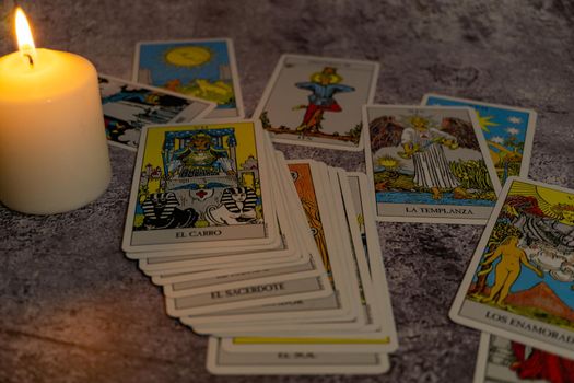 older white-haired woman reading tarot cards on a wooden table with candle