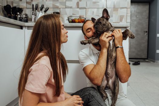 Woman and Man Having Fun Time at Kitchen with Their Dog, French Bulldog with Family at Home