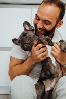 Cheerful Caucasian Man Hugging His Lovely Pet Small French Bulldog