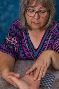 older white-haired woman reading tarot cards on a wooden table with candle