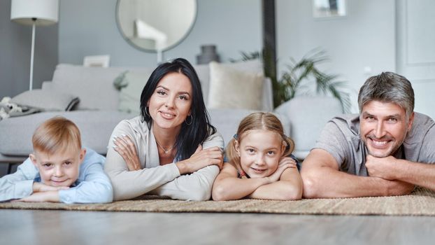 happy family with children lying on the floor in the living room. photo with a copy space.