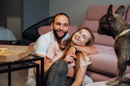 Cheerful Man and Woman Hugging at Home and Smiling to French Bulldog Pet
