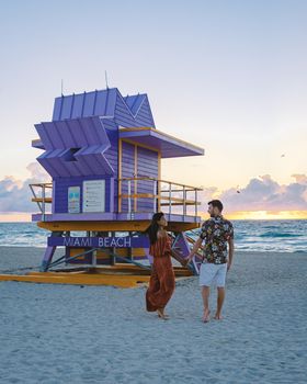 Miami Beach, a couple on the beach at Miami Florida, lifeguard hut Miami Asian women and caucasian men on the beach during sunset