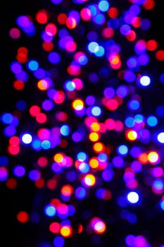 Colorful defocused holiday lights at Christmas night. Decorations made of multicolored LED lights during the holiday season. Holiday concept.