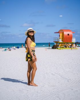 Miami Beach, a couple on the beach at Miami Florida, lifeguard hut Miami Asian women and caucasian men on the beach during sunset. Happy women walking on the white beach