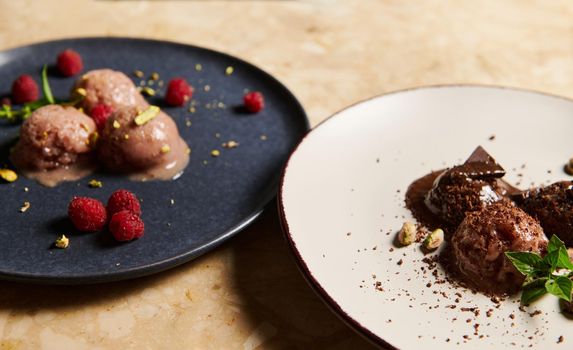 Selective focus. Still life with food. Close-up. Partial view of refreshing raw vegan sorbets, garnished with pistachios, raspberries on ceramic plates on the marble table background. Healthy eating.