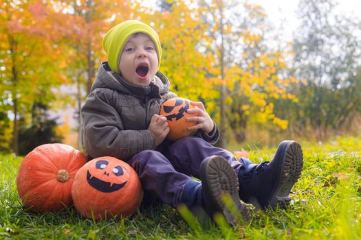 A boy with a Halloween pumpkin with eyes . The feast of fear. Halloween. An orange pumpkin with eyes. An article about Halloween.