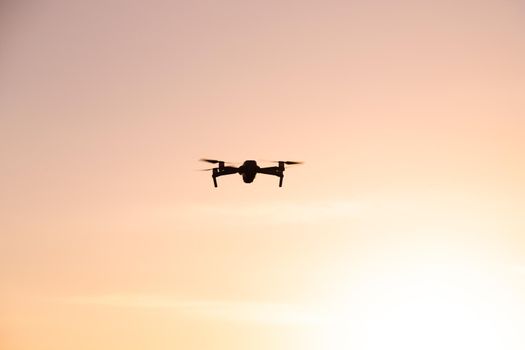 The drone is in flight at sunset . Video shooting from above. An article about the choice of a quadrocopter. Pros and cons of the drone. Sunset