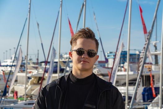 Portrait of a young guy on the background of the sea and yachts.