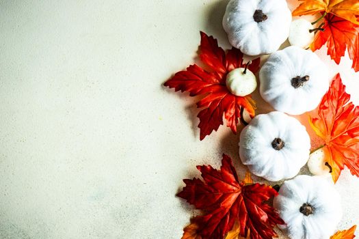 Frame made with fake autumnl leaves and harvest vegetables on the concrete background