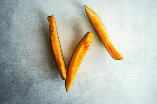 Ripe cantaloupe melon slices on minimalistic concrete background