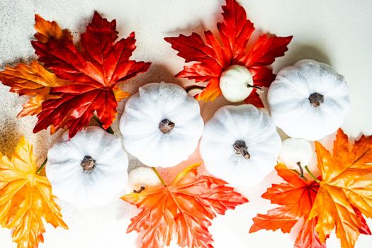 Frame made with fake autumnl leaves and harvest vegetables on the concrete background