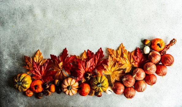 Frame made with fake autumnl leaves and harvest vegetables on the concrete background