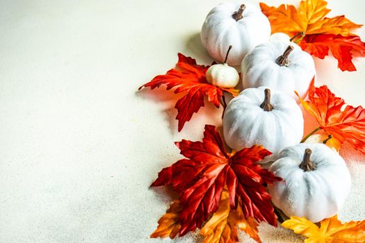 Frame made with fake autumnl leaves and harvest vegetables on the concrete background