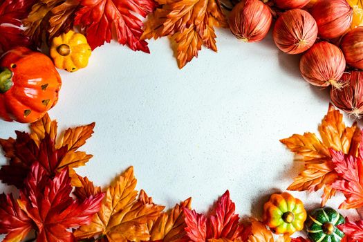 Frame made with fake autumnl leaves and harvest vegetables on the concrete background