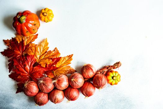 Frame made with fake autumnl leaves and harvest vegetables on the concrete background