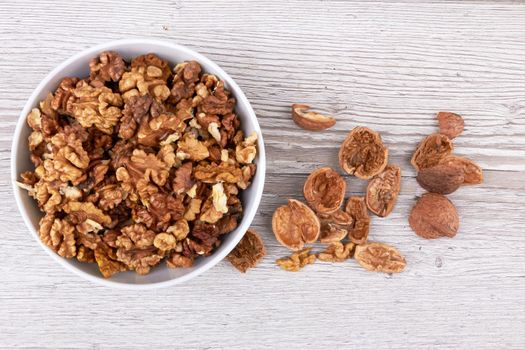 Walnuts in white bowl on wooden surface