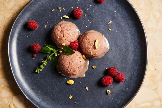 Flat lay. Refreshing ice cream. Scoops of healthy raw vegan raspberry sorbet topped with pistachio, lemon basil on a serving plate on marble background. Food still life. Summer concepts. Copy space