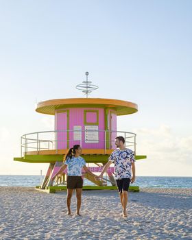 Miami Beach, a couple on the beach at Miami Florida, lifeguard hut Miami Asian women and caucasian men on the beach during sunset. man and woman watching sunrise