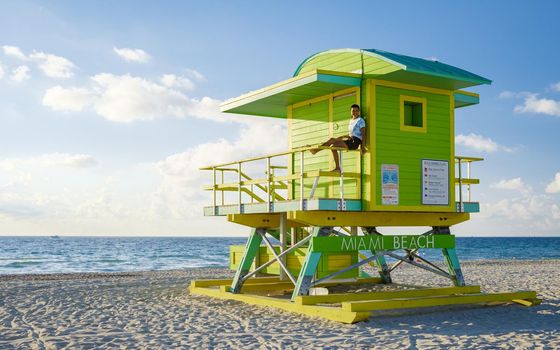 Miami Beach, a couple on the beach at Miami Florida, lifeguard hut Miami Asian women and caucasian men on the beach during sunset. man and woman watching sunrise