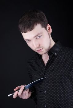 Portrait of depressive man with knife in black cloth