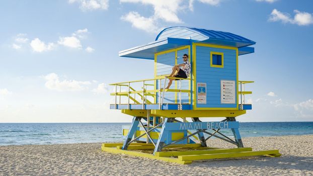 Miami beach, young men on the beach, lifeguard hut Miami beach Florida. caucasian men on the beach during sunrise. Caucasian men relax watching ocean