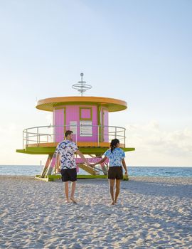 Miami Beach, a couple on the beach at Miami Florida, lifeguard hut Miami Asian women and caucasian men on the beach during sunset. man and woman watching sunrise