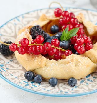 Fruit tart with red currants sprinkled with powdered sugar on a white table