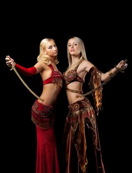 Two blond girl stand with saber - arabian traditional costume