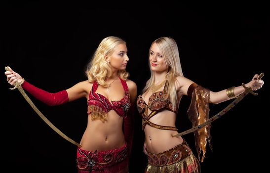 Two blond girl stand with saber - arabian costume