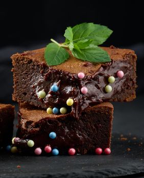 Baked pieces of chocolate brownie pie on a black table