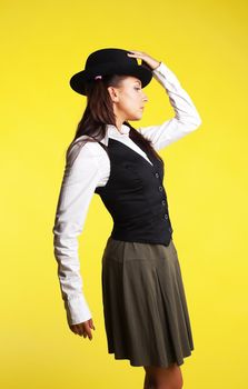 Beauty woman posing like school-girl in hat on yellow background