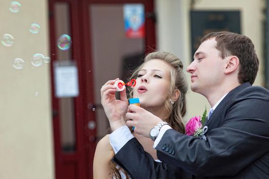 just married young couple blow bubbles in town
