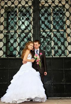 Young Wedding couple stand near huge temple gate