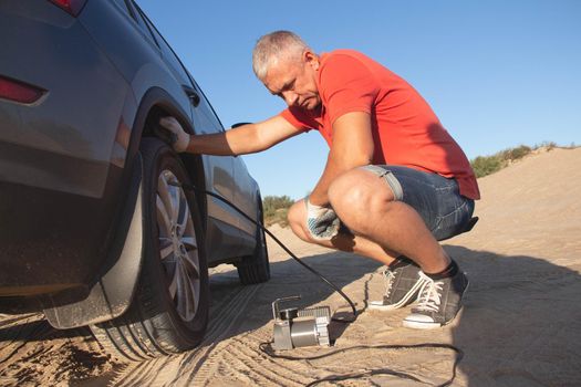 A man checks tire pressure. Travel to the sea by car.