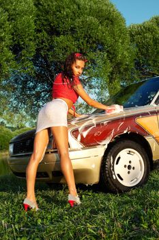 Sexy woman washing a car at summer sunset - pin-up style