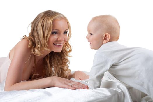 Pretty mother look at cute baby in white bed isolated