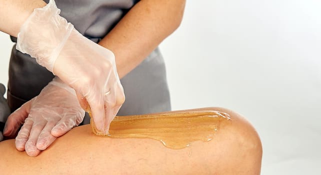 Sugar paste for light depilation. Depilation with sugar paste in the salon on a white background.