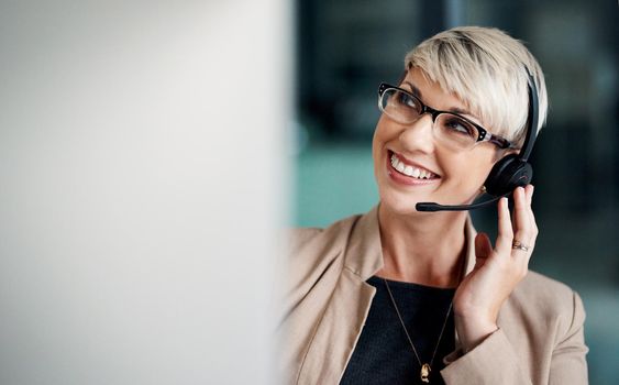 Keeping the line of communication open for customers. a young businesswoman wearing a headset while working on a computer in an office