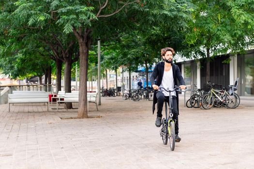 stylish young man riding his bike through the city, urban lifestyle and sustainable mobility concept, copy space for text